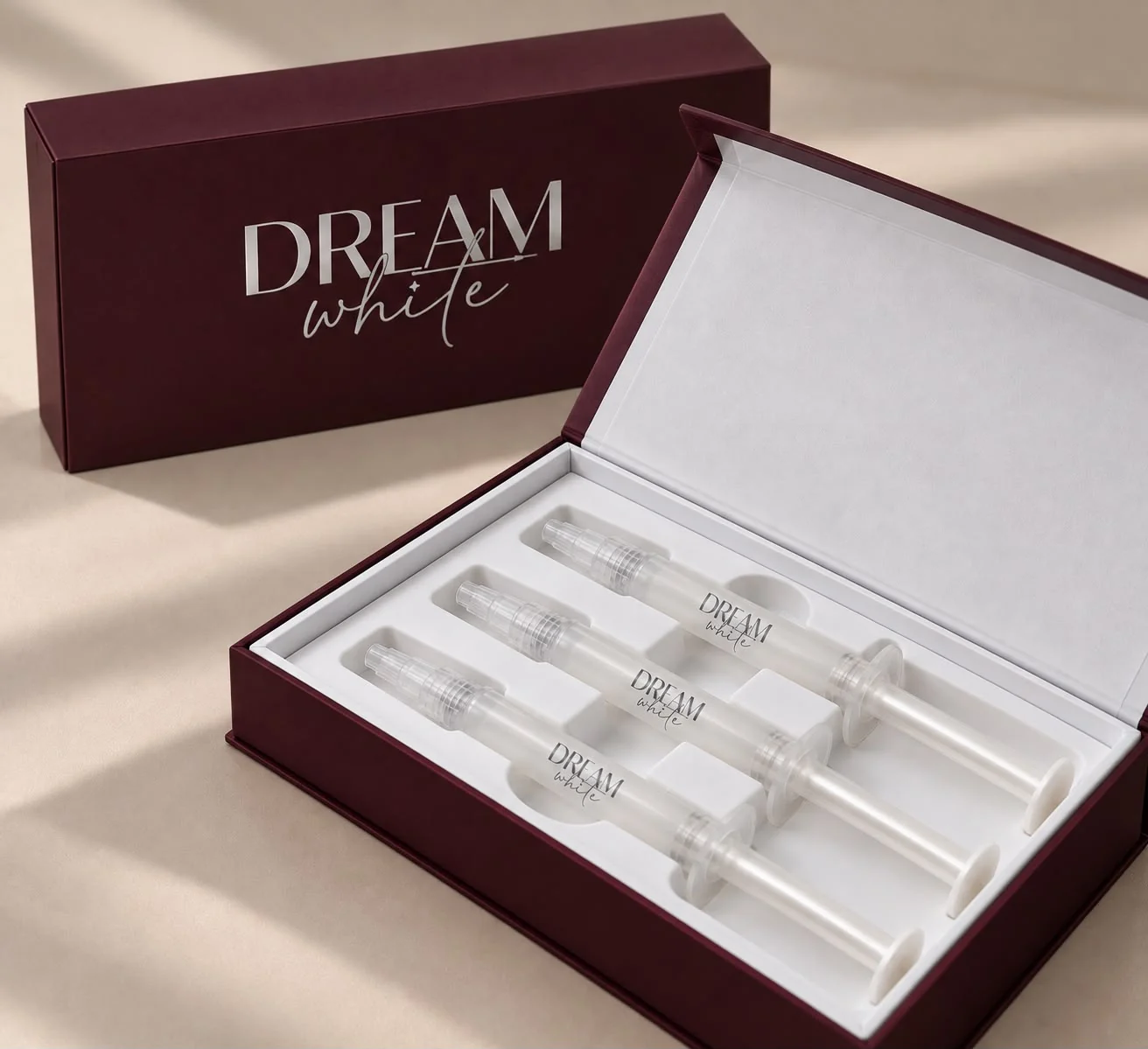 Geöffnete Dreamwhite-Box mit drei Gel-Applikatoren, dahinter die geschlossene Box mit silbernem Logo
